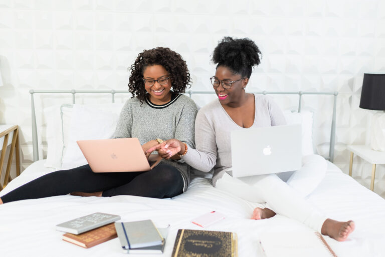 A group of diverse female entrepreneurs smiling and collaborating over a business planning session.